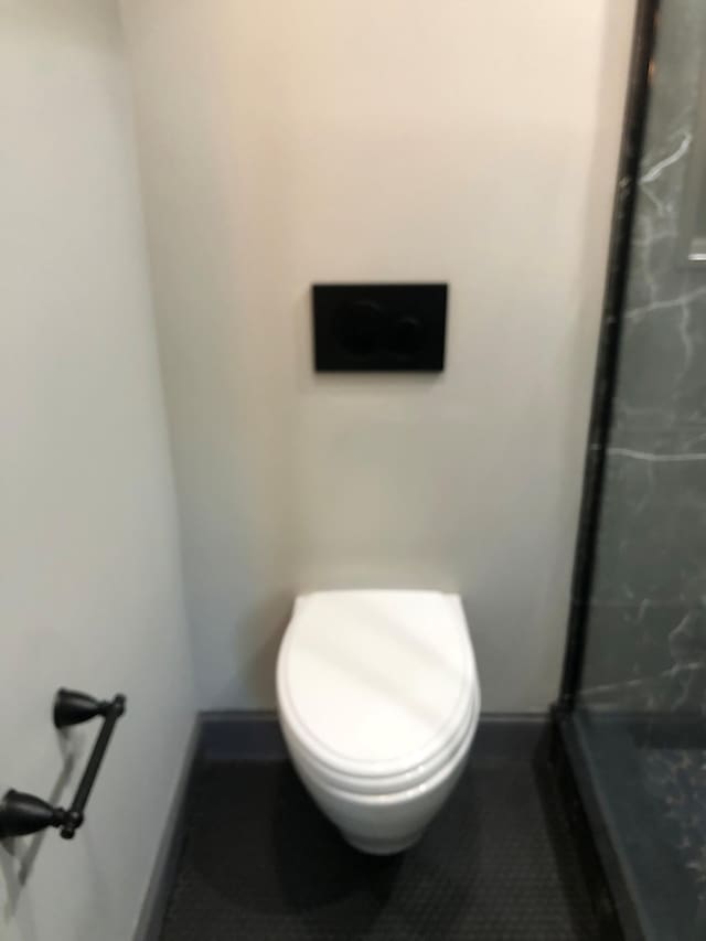 bathroom with baseboards, toilet, tile patterned floors, and a stall shower