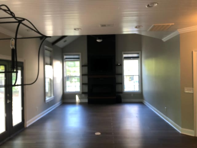 unfurnished living room with visible vents, baseboards, ornamental molding, and dark wood-style floors