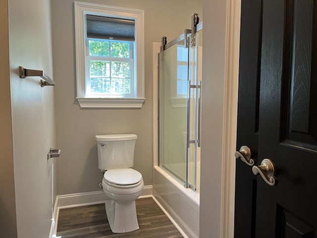 full bath featuring enclosed tub / shower combo, baseboards, toilet, and wood finished floors