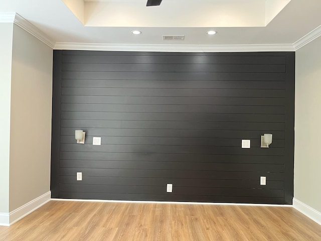 spare room featuring light wood-style floors, visible vents, baseboards, and ornamental molding
