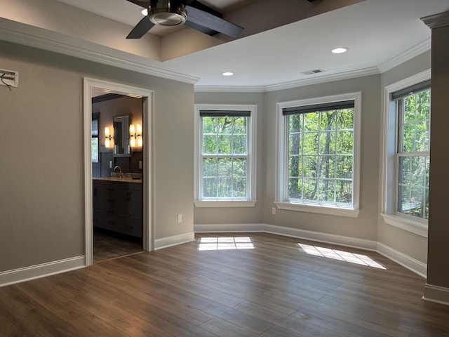 empty room with baseboards, visible vents, ceiling fan, crown molding, and dark wood-type flooring