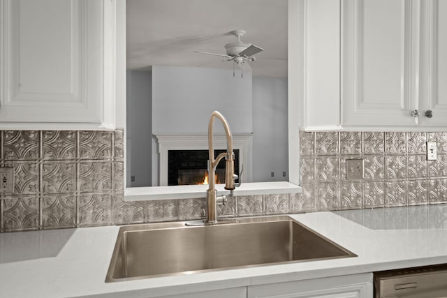 kitchen featuring a ceiling fan, decorative backsplash, dishwashing machine, light countertops, and a sink