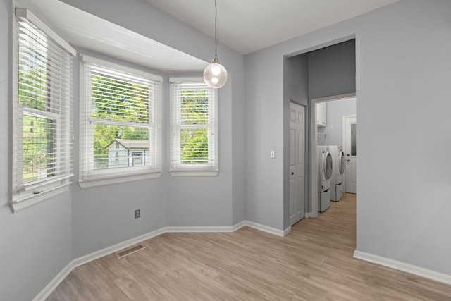 unfurnished dining area with separate washer and dryer, baseboards, visible vents, and light wood-type flooring