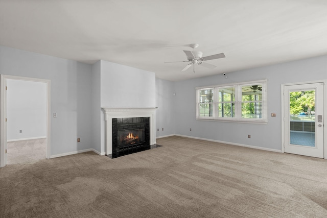 unfurnished living room with carpet floors, ceiling fan, a fireplace with flush hearth, and baseboards
