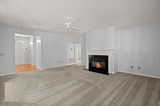 unfurnished living room featuring ceiling fan, visible vents, a tiled fireplace, carpet floors, and baseboards