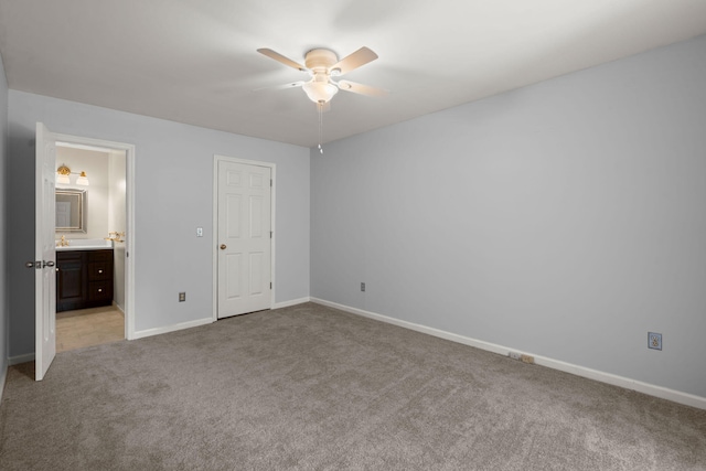 unfurnished bedroom featuring connected bathroom, baseboards, light carpet, and ceiling fan
