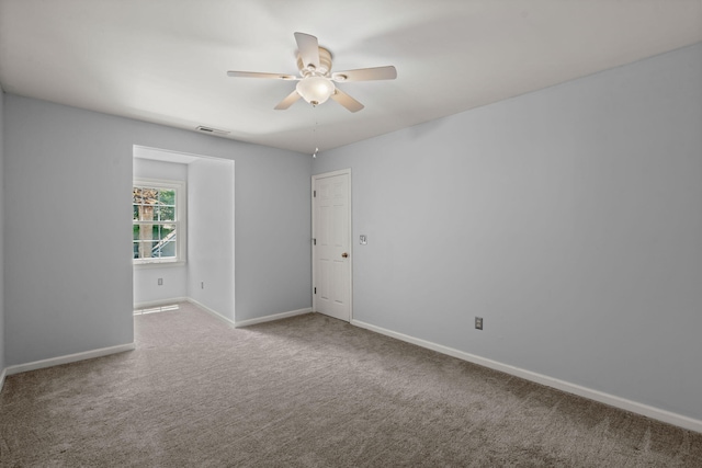 unfurnished room with baseboards, ceiling fan, carpet, and visible vents