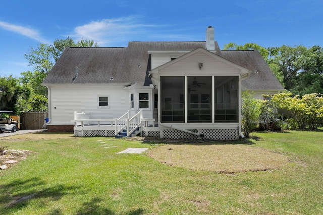rear view of house featuring a lawn, a chimney, a sunroom, and a shingled roof