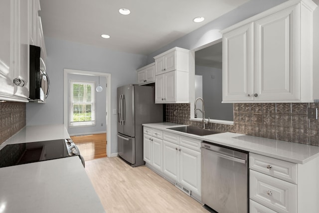 kitchen featuring a sink, white cabinetry, appliances with stainless steel finishes, and light wood-style flooring