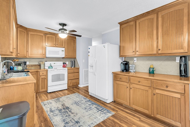 kitchen featuring tasteful backsplash, light wood-type flooring, white appliances, and sink