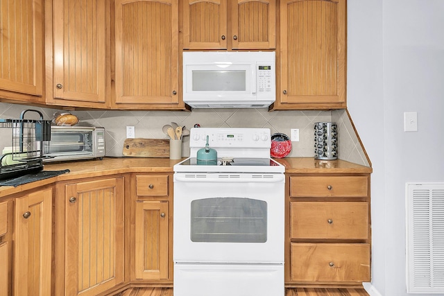 kitchen with light wood-type flooring, tasteful backsplash, and white appliances