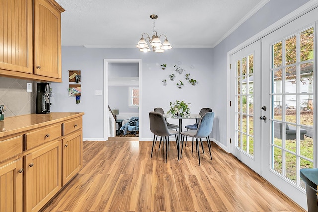 dining room with light hardwood / wood-style floors, an inviting chandelier, french doors, and ornamental molding