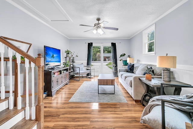 living room with ornamental molding, light wood-type flooring, a textured ceiling, and ceiling fan