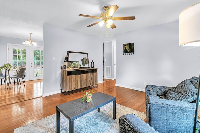 living room with ceiling fan with notable chandelier, wood-type flooring, and a textured ceiling