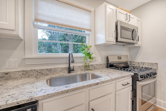 kitchen featuring white cabinetry, sink, light stone counters, and stainless steel appliances