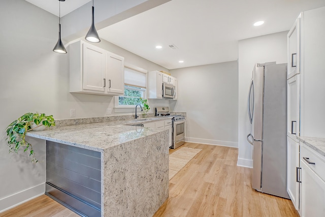 kitchen with decorative light fixtures, sink, white cabinets, light stone counters, and stainless steel appliances