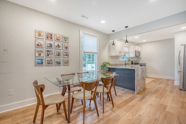 dining area featuring electric panel and light wood-type flooring