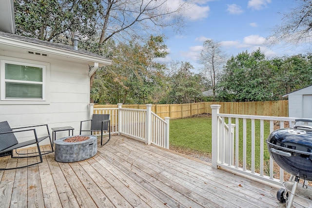 deck with area for grilling, a yard, and an outdoor fire pit