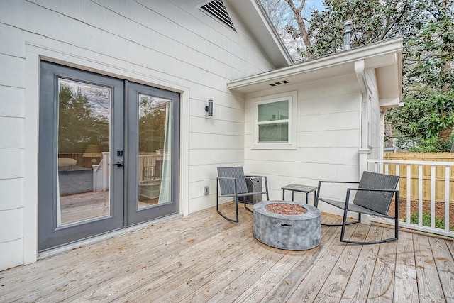 wooden terrace with a fire pit and french doors