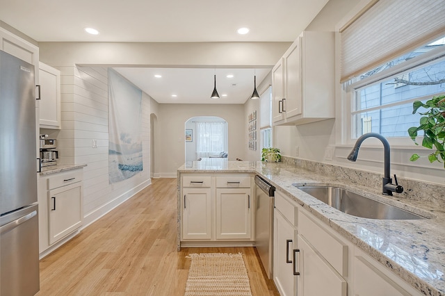 kitchen with sink, white cabinetry, decorative light fixtures, kitchen peninsula, and stainless steel appliances