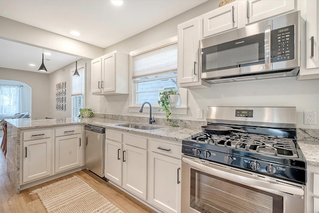 kitchen featuring sink, appliances with stainless steel finishes, kitchen peninsula, light hardwood / wood-style floors, and white cabinets