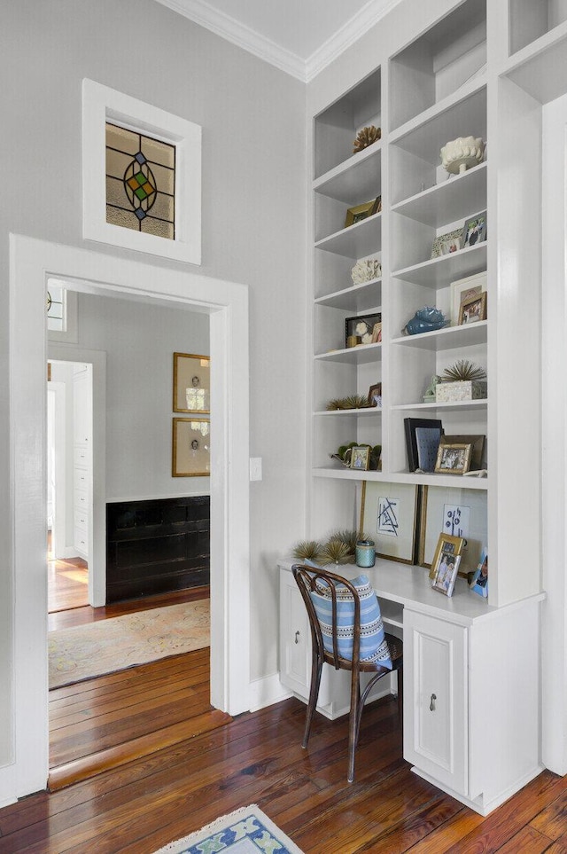 home office featuring dark hardwood / wood-style flooring, built in desk, and ornamental molding