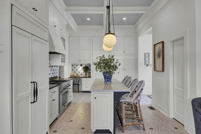 kitchen featuring a kitchen bar, premium appliances, a kitchen island, pendant lighting, and white cabinetry