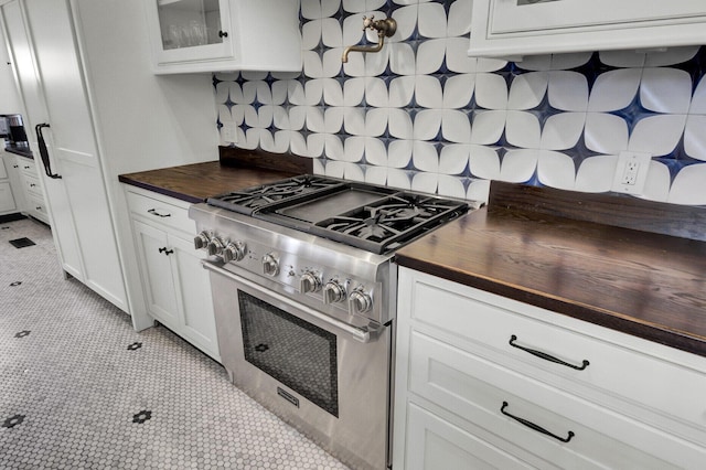 kitchen featuring tasteful backsplash, high end stainless steel range, white cabinets, and light tile patterned floors