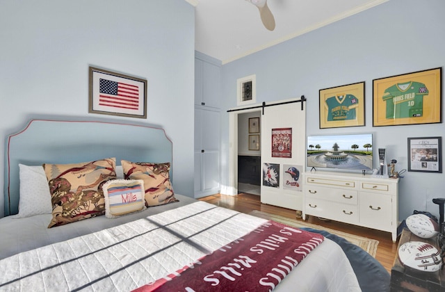 bedroom with a barn door, ceiling fan, and dark wood-type flooring