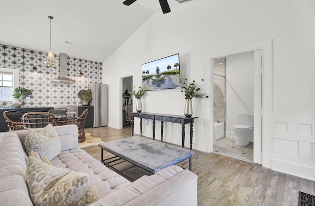 living room featuring light hardwood / wood-style floors, high vaulted ceiling, and ceiling fan