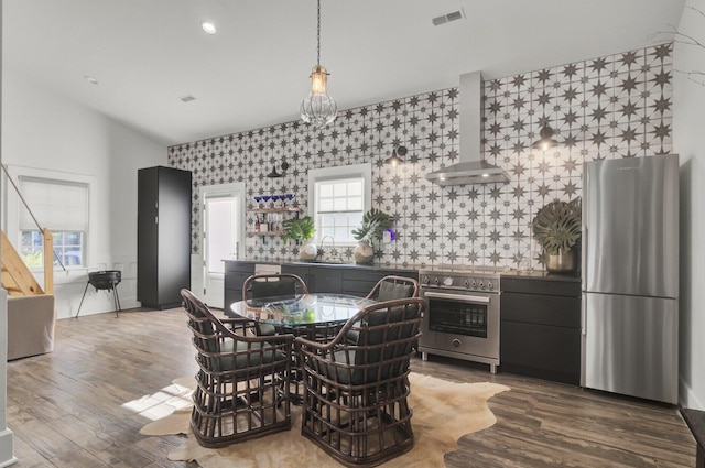 kitchen with appliances with stainless steel finishes, sink, dark hardwood / wood-style flooring, and wall chimney range hood