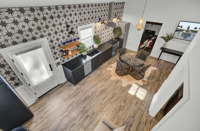 kitchen featuring hardwood / wood-style floors, decorative light fixtures, and wall chimney exhaust hood