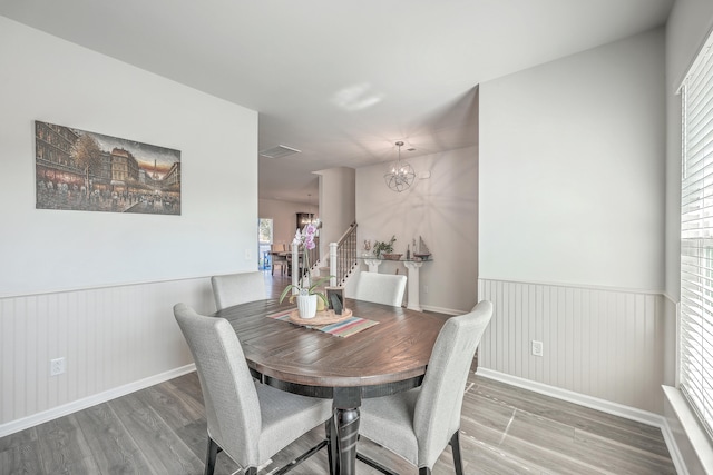 dining area with wood-type flooring and a notable chandelier