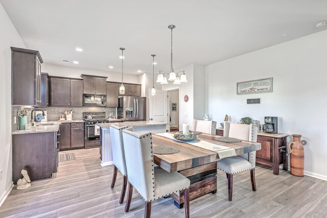 dining space featuring light hardwood / wood-style floors, an inviting chandelier, and sink