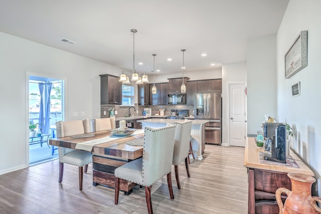 dining room with sink, light wood-type flooring, and an inviting chandelier