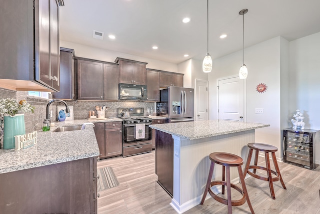 kitchen with light hardwood / wood-style flooring, beverage cooler, stainless steel appliances, and a kitchen island