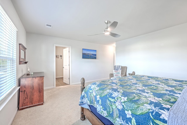 carpeted bedroom with ensuite bath and ceiling fan