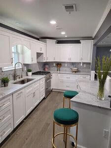 kitchen featuring visible vents, dark wood-type flooring, a sink, white cabinetry, and stainless steel stove