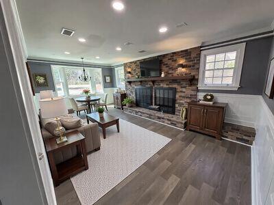 living room featuring wood finished floors, a wainscoted wall, visible vents, a fireplace, and crown molding