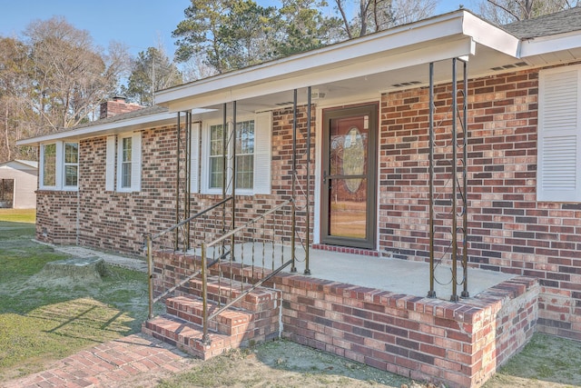 property entrance featuring brick siding and a chimney