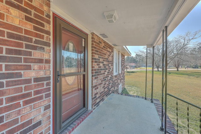 doorway to property featuring brick siding and a lawn