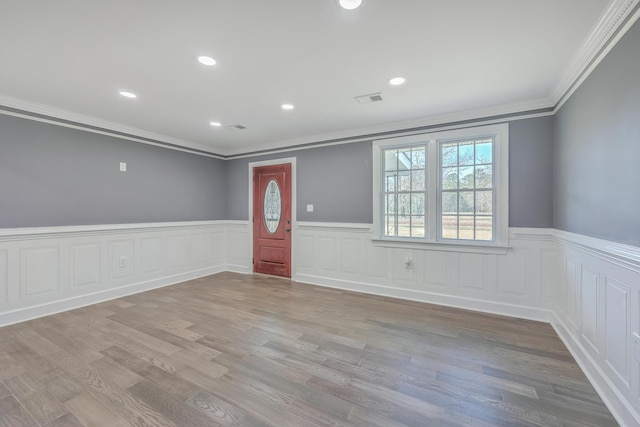 entrance foyer featuring visible vents, wood finished floors, recessed lighting, wainscoting, and crown molding