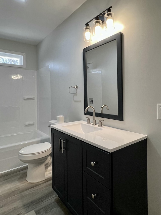 bathroom with toilet, vanity,  shower combination, and wood finished floors