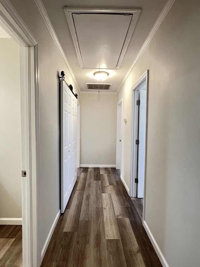 corridor featuring visible vents, dark wood finished floors, crown molding, baseboards, and attic access