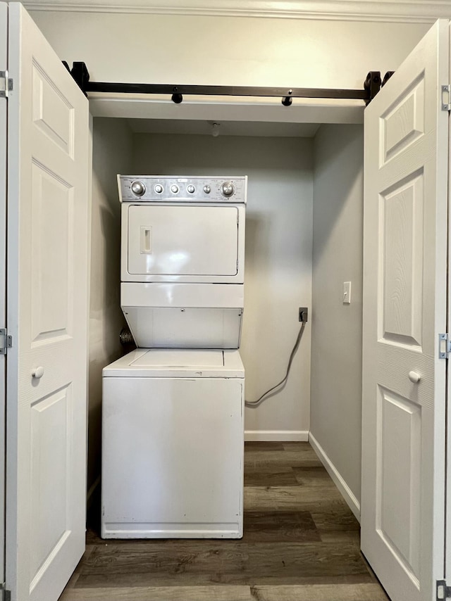 laundry room with dark wood-style floors, laundry area, stacked washer / drying machine, and baseboards