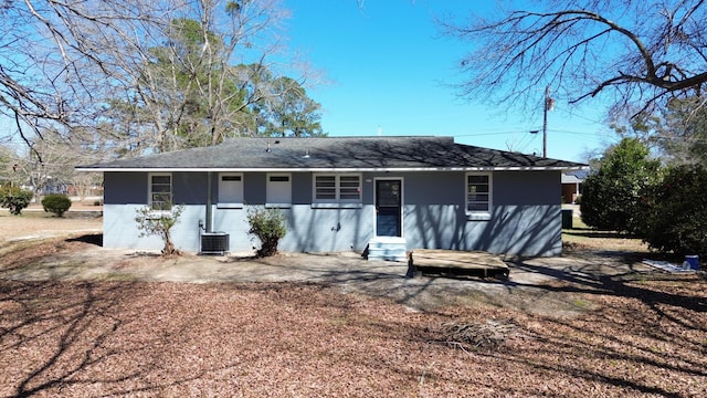 back of house featuring central air condition unit and a shingled roof