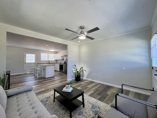 living area with baseboards, a ceiling fan, dark wood-style flooring, and crown molding