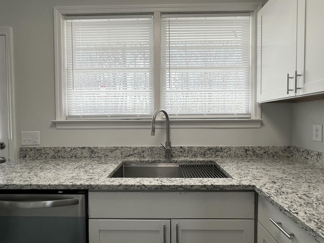 kitchen with a sink, white cabinets, light stone countertops, and stainless steel dishwasher