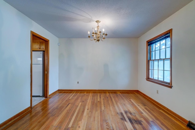 5322 Chantilly Ln, North Charleston, SC 29418 - spare room featuring a chandelier, light wood-style flooring, baseboards, and a textured ceiling