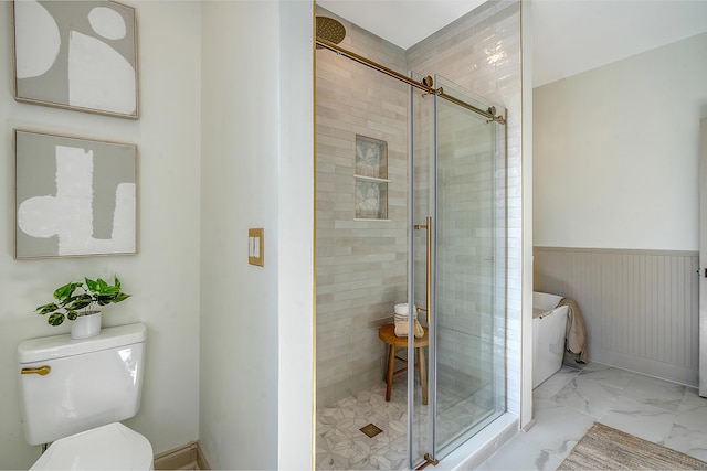 bathroom featuring a shower with door and toilet